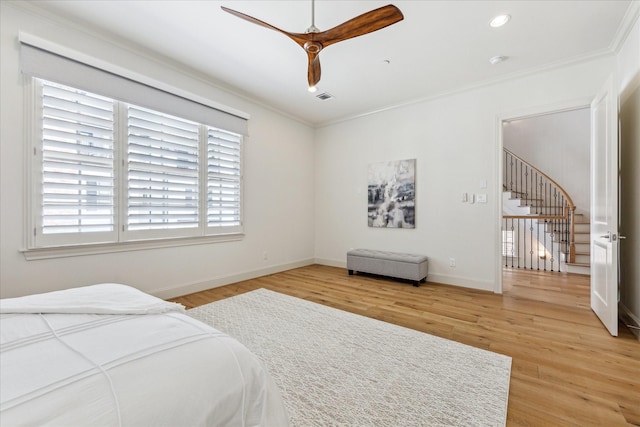 bedroom featuring visible vents, ornamental molding, light wood-type flooring, baseboards, and ceiling fan