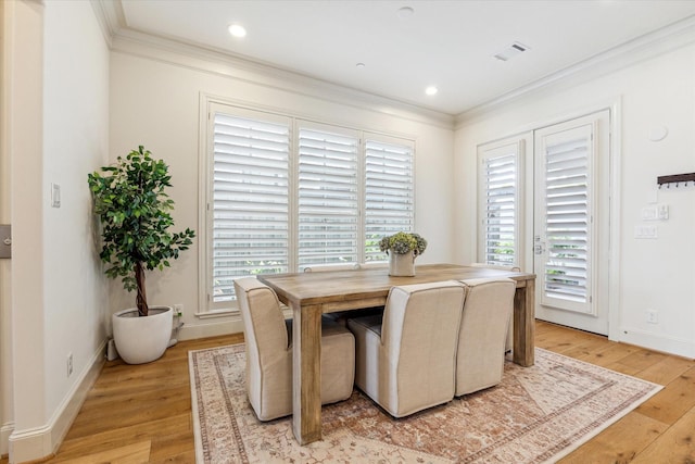 dining space featuring light wood-style flooring, visible vents, baseboards, and ornamental molding