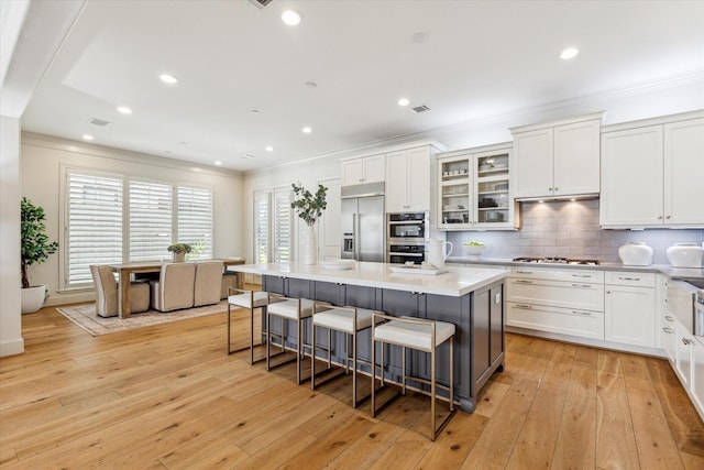 kitchen with white cabinets, a breakfast bar, light wood-style flooring, and built in refrigerator