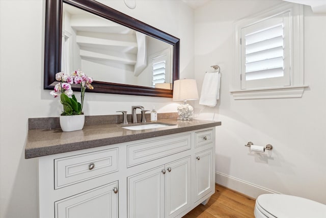 half bathroom with toilet, vanity, and wood finished floors