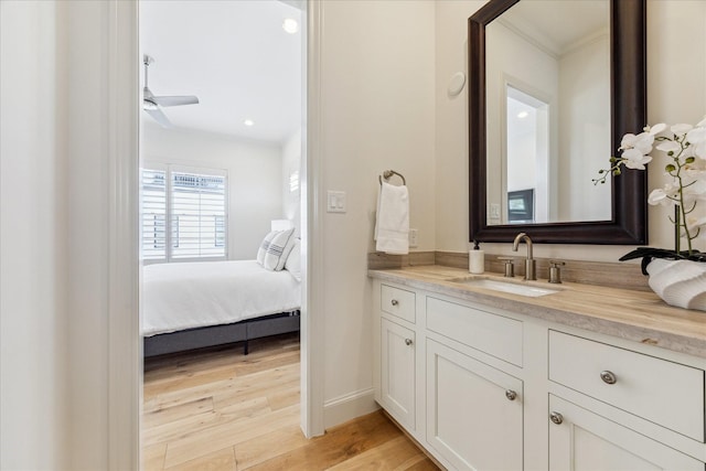 ensuite bathroom featuring vanity, baseboards, wood finished floors, crown molding, and ensuite bath