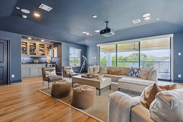 living room featuring recessed lighting, light wood-type flooring, visible vents, and bar