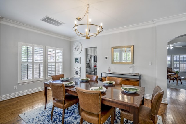 dining space with visible vents, crown molding, wood finished floors, baseboards, and a notable chandelier