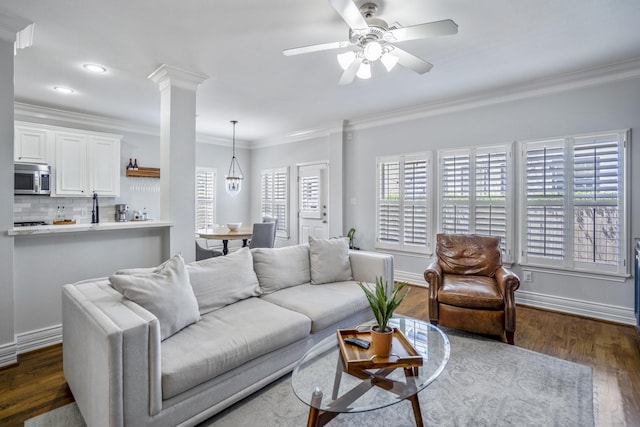 living area with ornamental molding, ceiling fan, a wealth of natural light, and dark wood-style floors