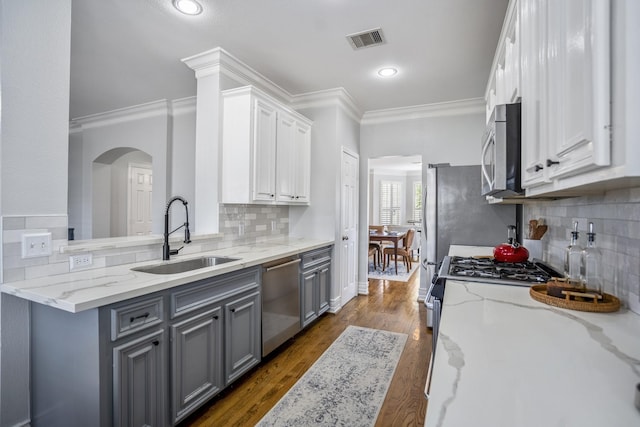 kitchen with crown molding, appliances with stainless steel finishes, a sink, gray cabinets, and visible vents