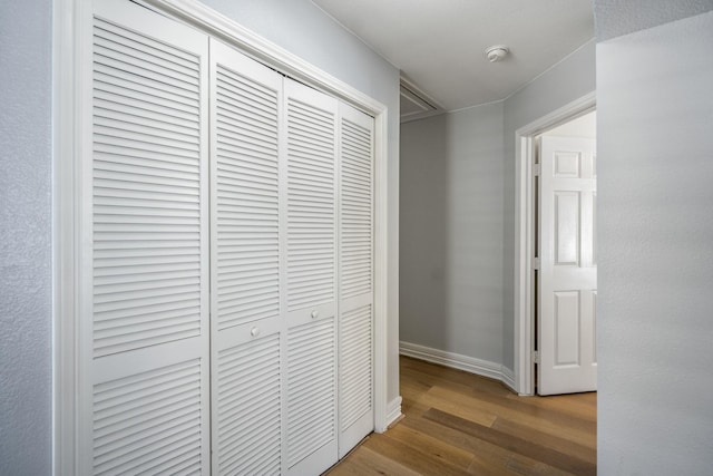 corridor featuring baseboards and wood finished floors