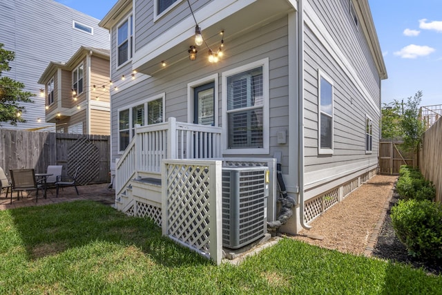rear view of property with a fenced backyard, a wooden deck, and central AC unit