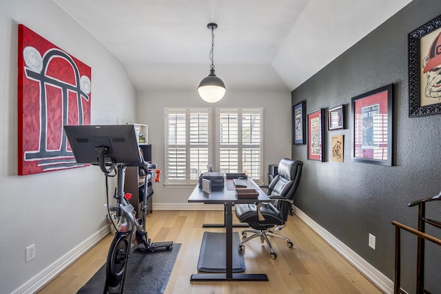 office area with baseboards, a textured wall, wood finished floors, and lofted ceiling