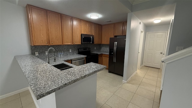 kitchen featuring light tile patterned floors, a sink, a peninsula, tasteful backsplash, and appliances with stainless steel finishes