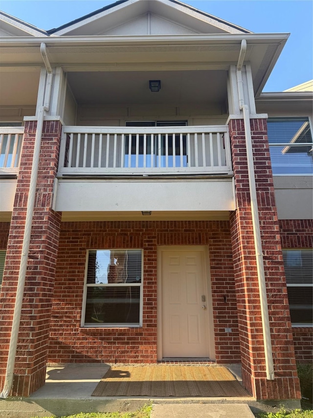 view of front of property with brick siding and a balcony