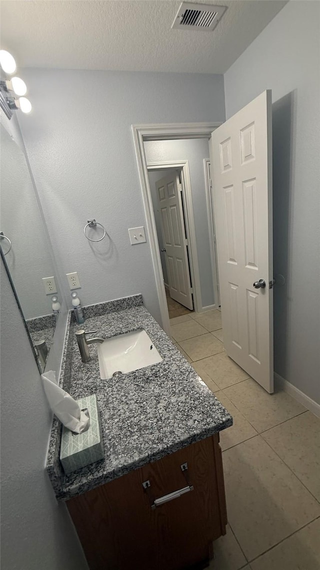 bathroom with tile patterned flooring, visible vents, vanity, baseboards, and a textured ceiling