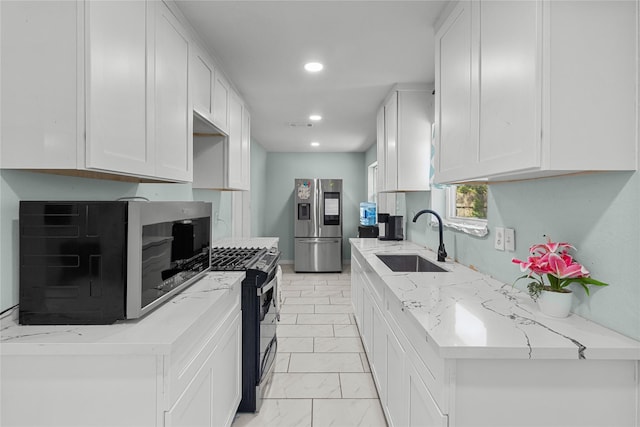 kitchen featuring white cabinets, a sink, recessed lighting, light stone counters, and appliances with stainless steel finishes