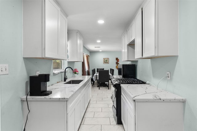 kitchen featuring marble finish floor, light stone counters, black range with gas stovetop, a sink, and white cabinetry