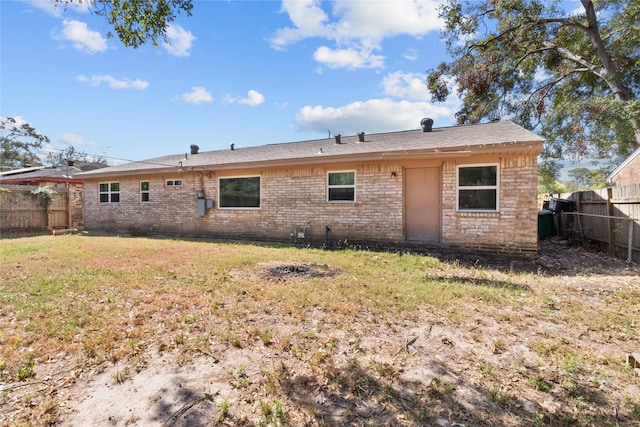 rear view of house featuring a fenced backyard, brick siding, and a yard