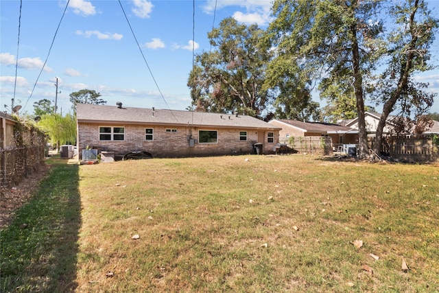 rear view of property with fence private yard, brick siding, a yard, and central AC