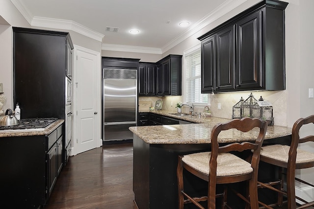 75 Colonial Row Dr, The Woodlands, TX 77380 - kitchen with a peninsula, a sink, visible vents, built in appliances, and dark cabinets