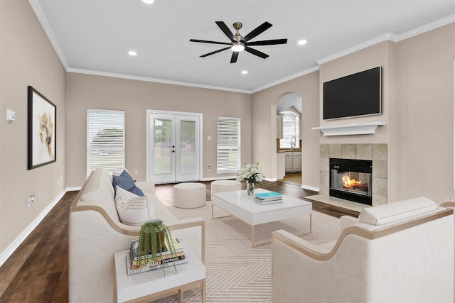 living area with recessed lighting, a tile fireplace, a ceiling fan, baseboards, and wood finished floors