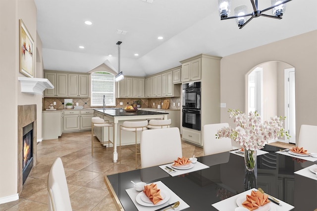 dining area featuring lofted ceiling, light tile patterned floors, a chandelier, arched walkways, and recessed lighting