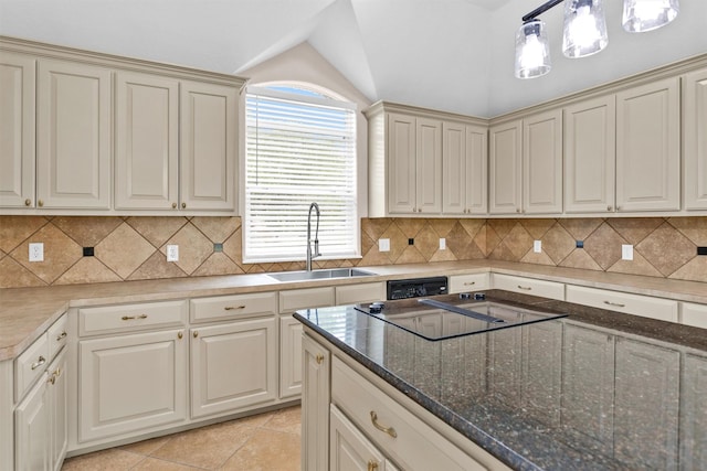 kitchen with black electric stovetop, cream cabinetry, lofted ceiling, and a sink
