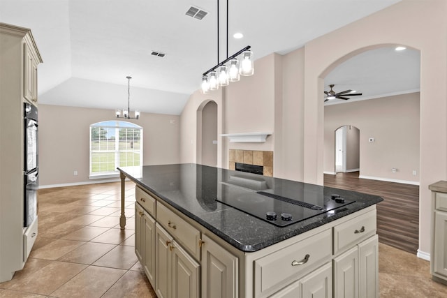 kitchen with a tiled fireplace, arched walkways, decorative light fixtures, ceiling fan with notable chandelier, and visible vents