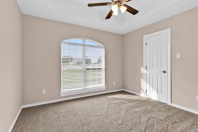 unfurnished room featuring carpet, a ceiling fan, a tray ceiling, and baseboards