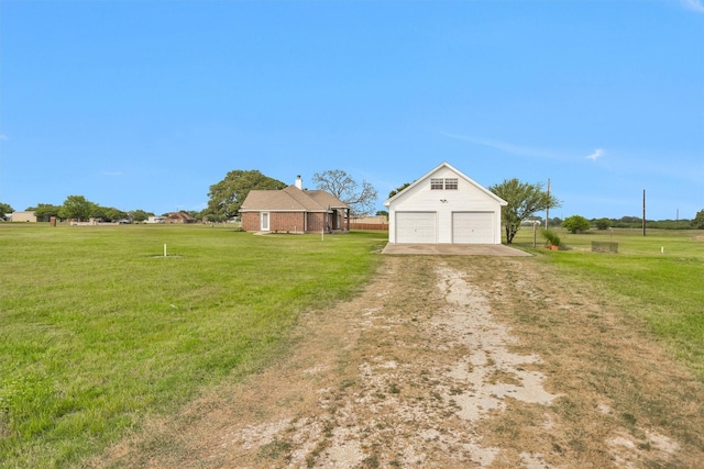 exterior space featuring driveway, a yard, a detached garage, and an outbuilding