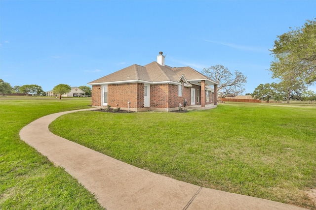 view of property exterior featuring a lawn, a chimney, and brick siding