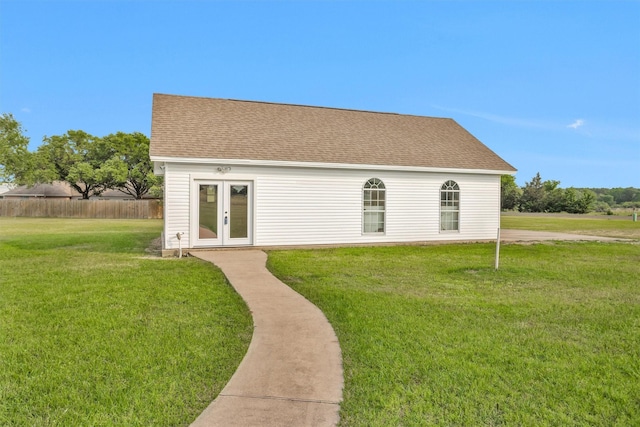 view of front of home featuring a shingled roof, a front yard, and french doors