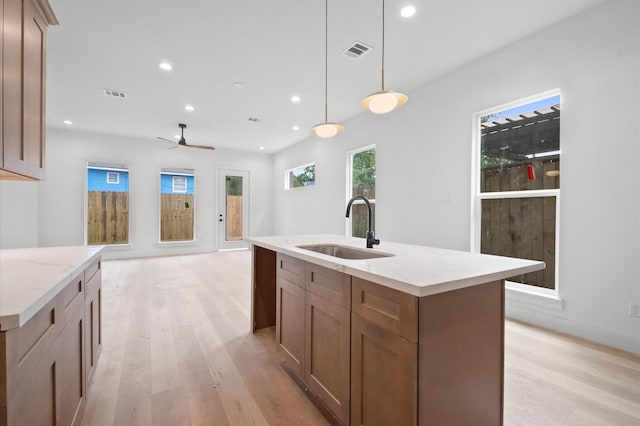 6703 Del Rio St, Houston, TX 77021 - kitchen with light wood-type flooring, recessed lighting, a center island with sink, a ceiling fan, and hanging light fixtures