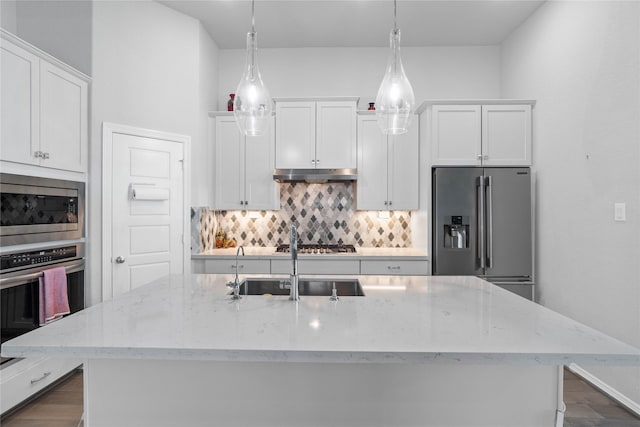 kitchen featuring stainless steel appliances, under cabinet range hood, white cabinetry, and tasteful backsplash