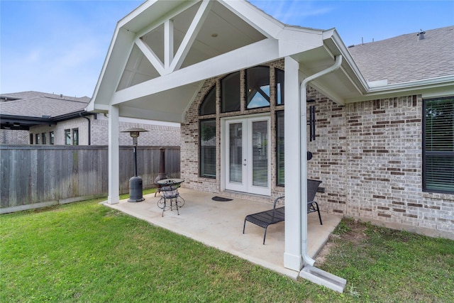 back of house with fence, a yard, roof with shingles, a patio, and brick siding