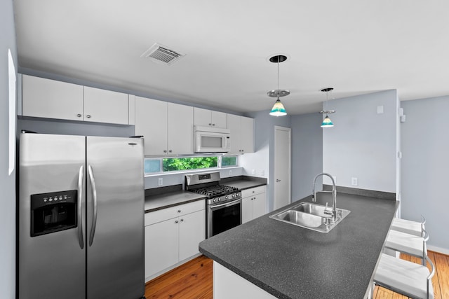 1522 Drew St, Houston, TX 77004 - kitchen with stainless steel appliances, a sink, dark countertops, a peninsula, and light wood-type flooring