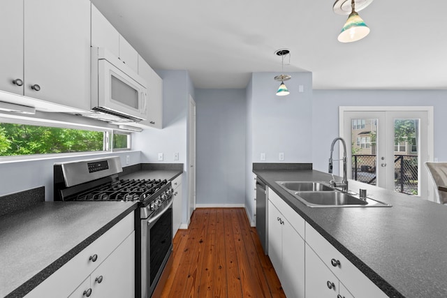1522 Drew St, Houston, TX 77004 - kitchen featuring stainless steel appliances, dark countertops, a sink, dark wood-type flooring, and white cabinetry