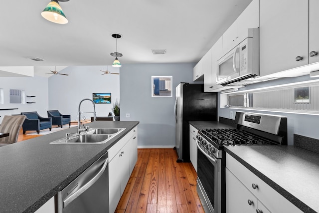 1522 Drew St, Houston, TX 77004 - kitchen featuring appliances with stainless steel finishes, a sink, dark countertops, white cabinets, and hanging light fixtures