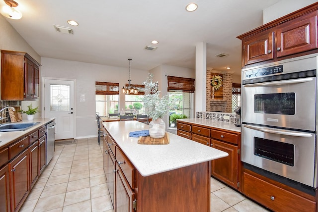 kitchen featuring backsplash, visible vents, a sink, a center island, and appliances with stainless steel finishes