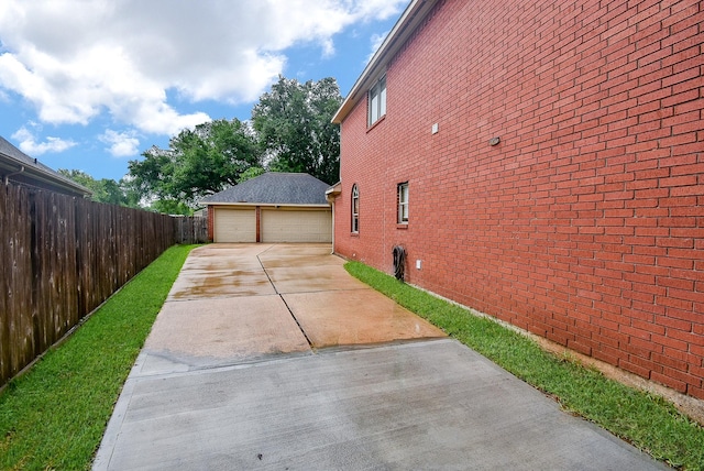 view of side of home featuring brick siding, a detached garage, fence, and an outdoor structure