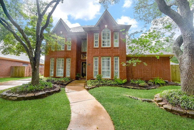 view of front facade featuring fence, a front lawn, and brick siding