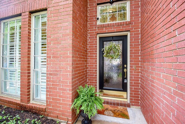 entrance to property featuring brick siding
