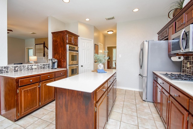 kitchen featuring light tile patterned flooring, stainless steel appliances, backsplash, visible vents, and a kitchen island
