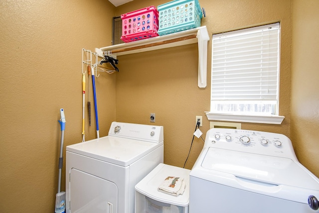 clothes washing area featuring separate washer and dryer, a textured wall, and laundry area