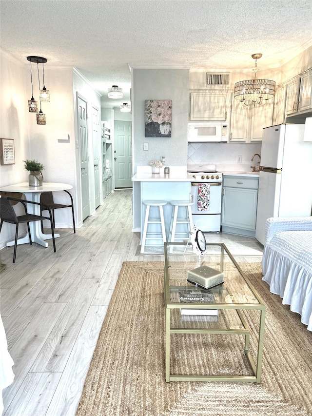 kitchen with white appliances, a textured ceiling, light wood-style floors, and crown molding