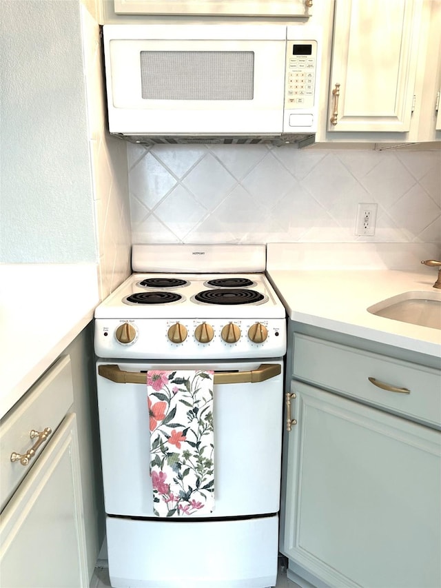 kitchen featuring light countertops, backsplash, a sink, and white appliances