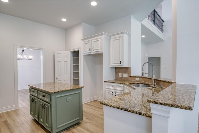 kitchen featuring green cabinetry, a sink, white cabinetry, and light wood-type flooring