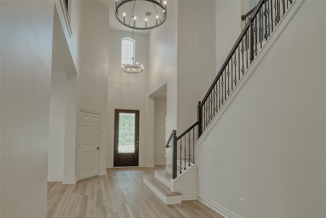 foyer entrance featuring a chandelier, wood finished floors, a high ceiling, and plenty of natural light