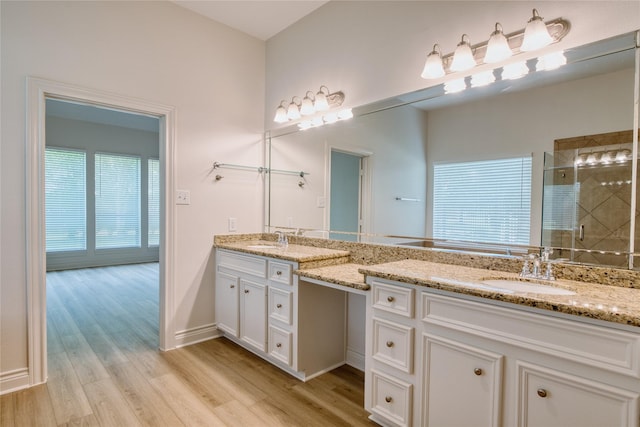 bathroom featuring wood finished floors, a shower stall, vanity, and baseboards