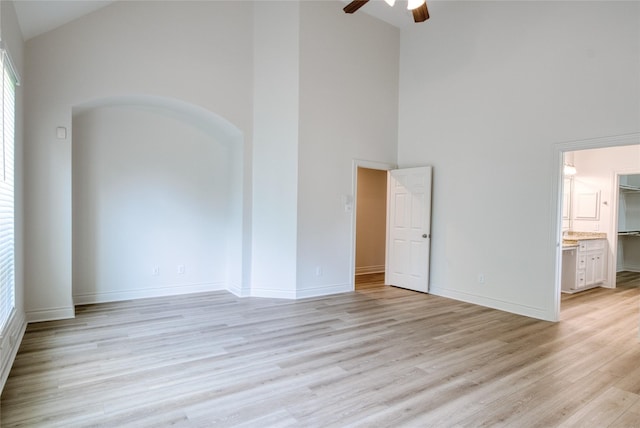 interior space featuring baseboards, high vaulted ceiling, a ceiling fan, and light wood finished floors