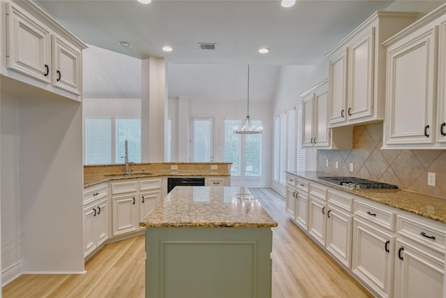 kitchen featuring tasteful backsplash, a sink, visible vents, stainless steel gas stovetop, and light wood finished floors