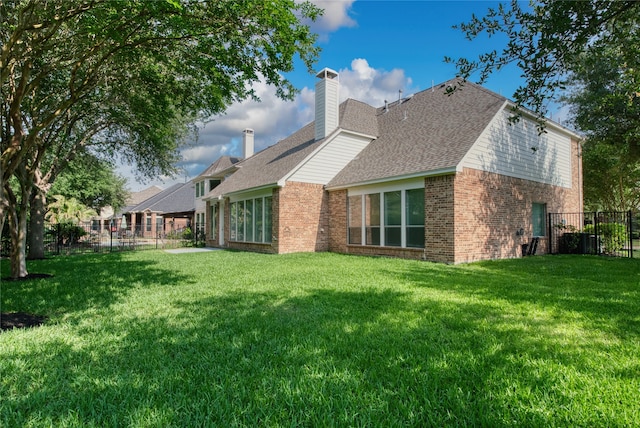 back of property with a chimney, brick siding, fence, and a lawn