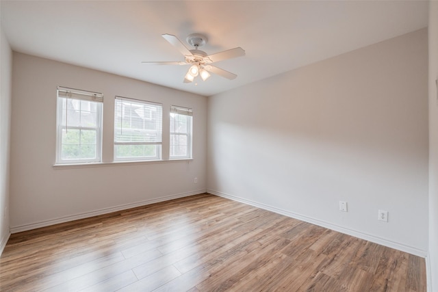 unfurnished room with wood finished floors, a ceiling fan, and baseboards