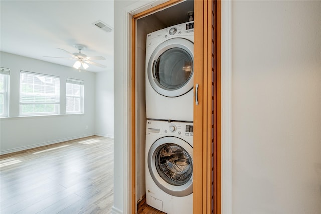 laundry room with stacked washer and dryer, light wood-style flooring, visible vents, ceiling fan, and laundry area